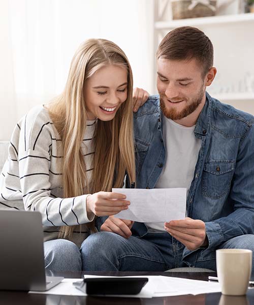 Man and woman reviewing financing paper while sitting on a couch